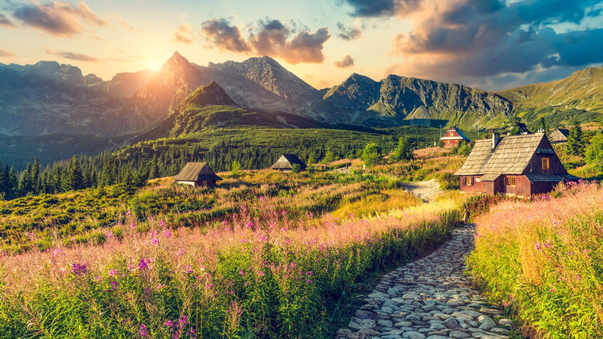 Spectacular scenery with tall mountains in the background, cobbled streets and traditional houses in the foreground. 