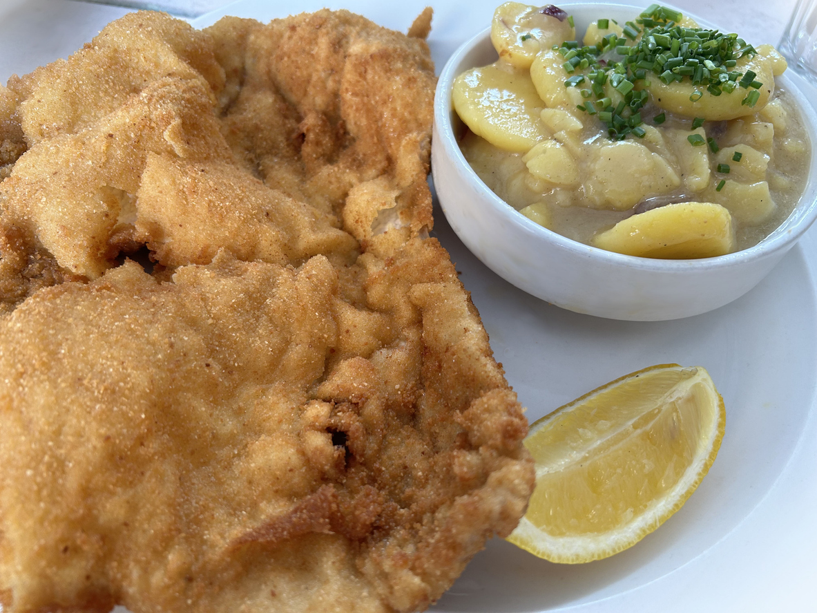 Wiener schnitzel and potato salad on a plate, with a lemon wedge