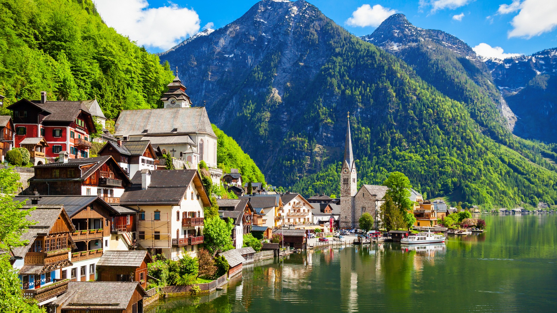 A picturesque town built by a lake with tall mountains in the background. 