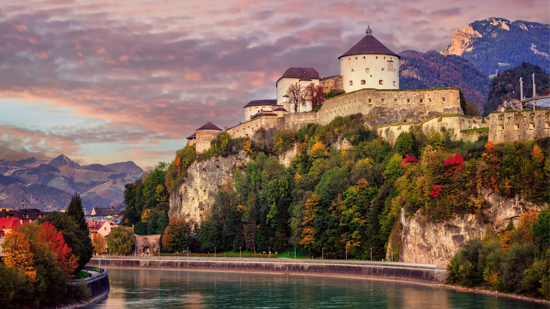 A fortress perched atop a rock overlooking a river. 