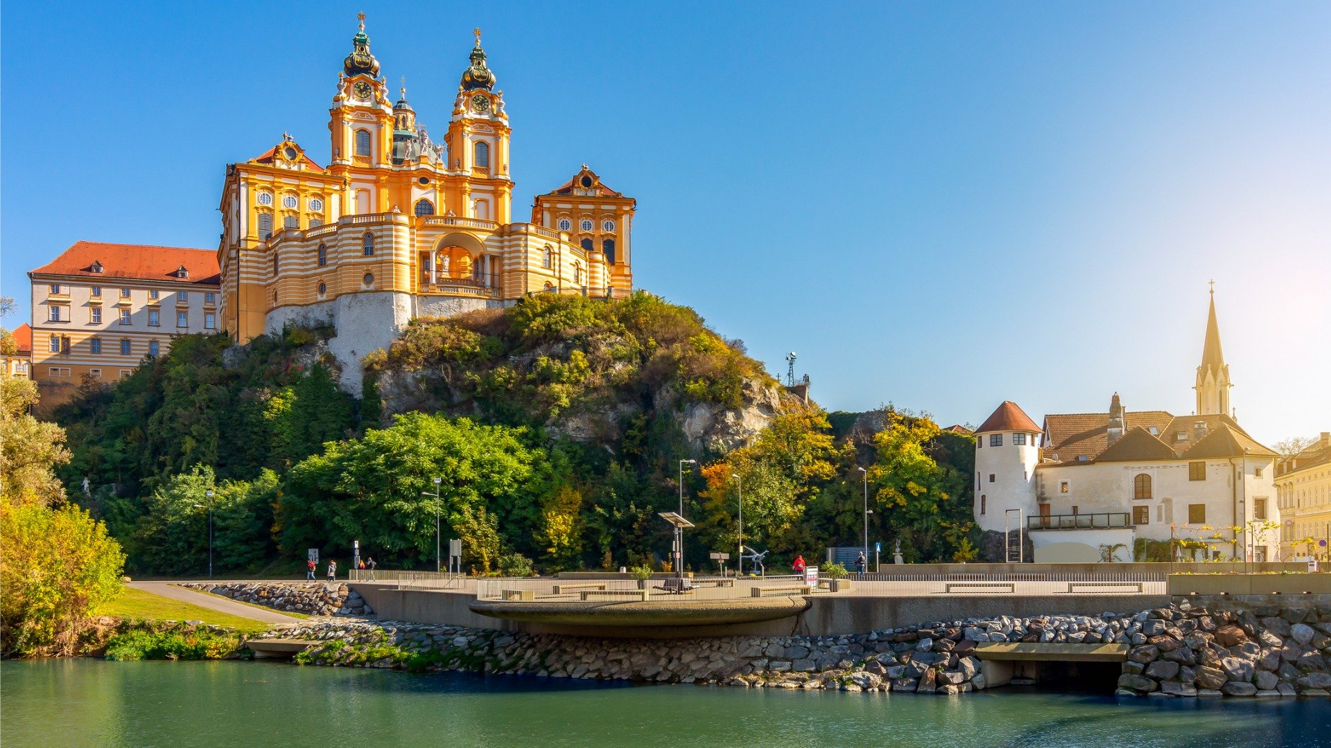 An imposing church built on a rock overlooking a quaint town and a river. 