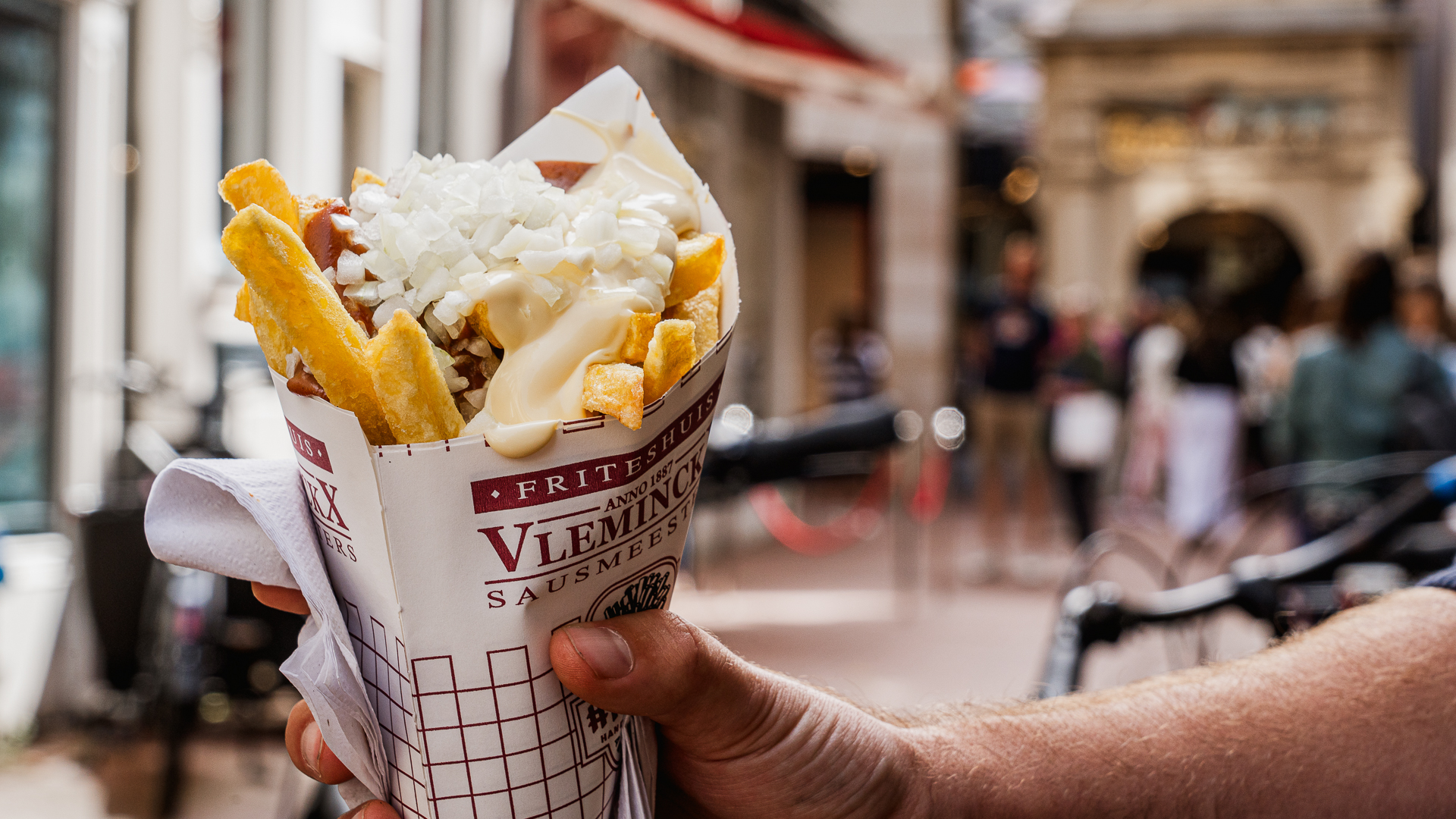 A cone of loaded fries at a busy Amsterdam street.