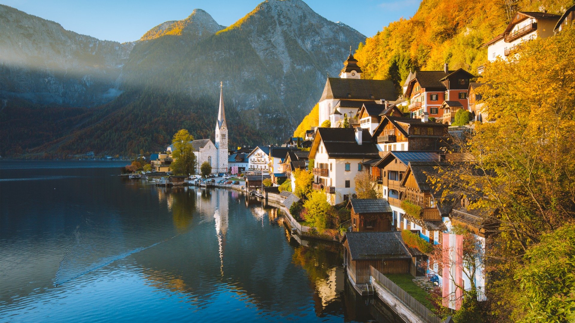 A quaint village built on the shore of a lake with tall mountains in the background. 