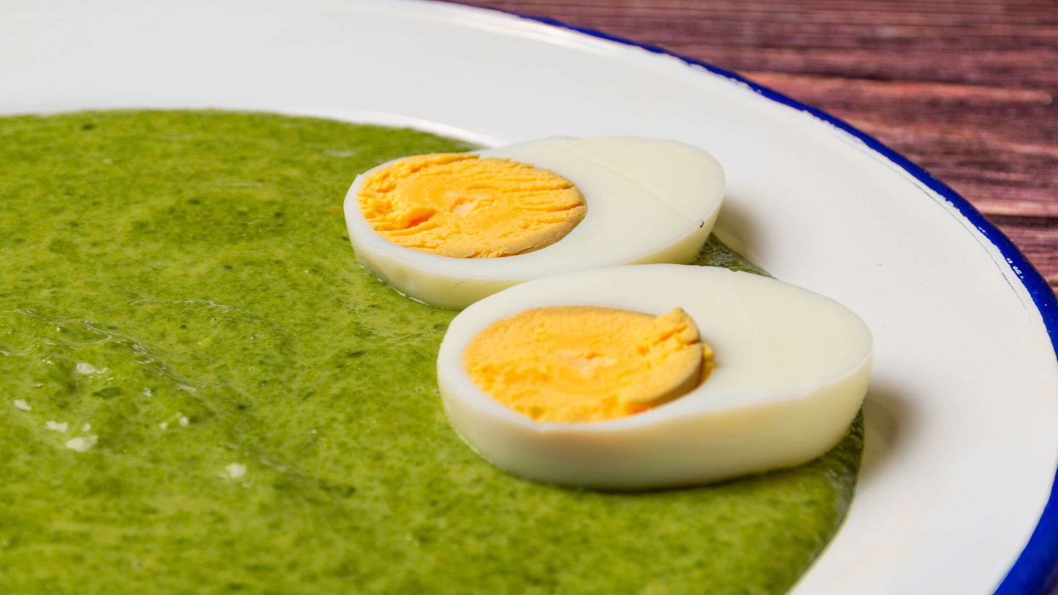 A close-up of Hungarian style creamed spinach with two hard-boiled egg halves on top.