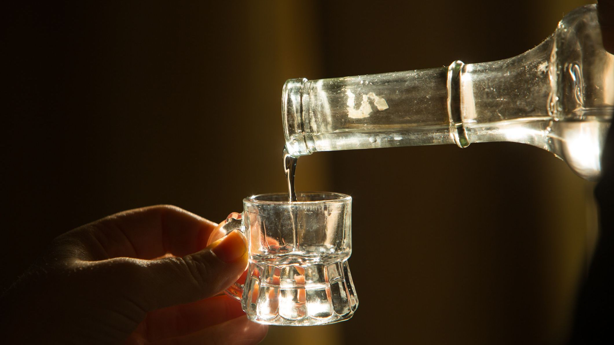 Palinka, the famous homemade Hungarian alcohol, pouring from a bottle to a small glass.