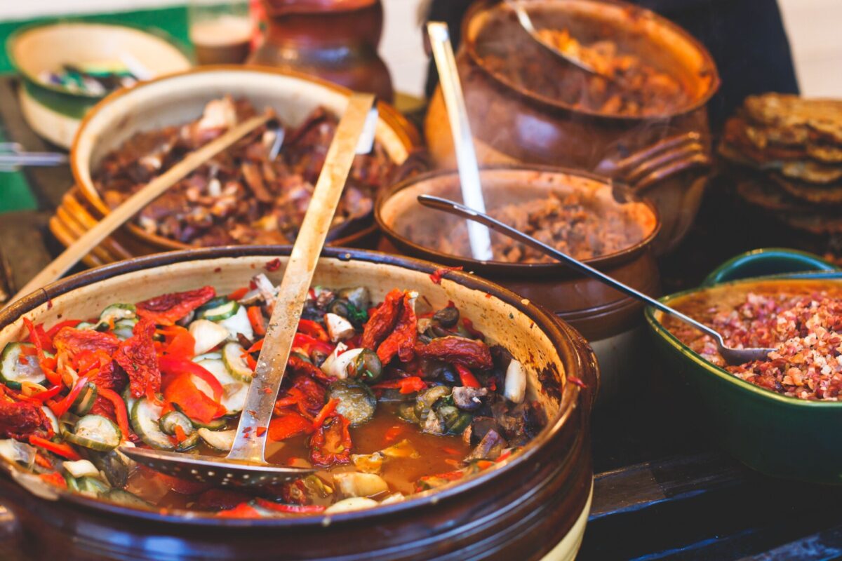 Several clay pots filled with various types of traditional Hungarian food.