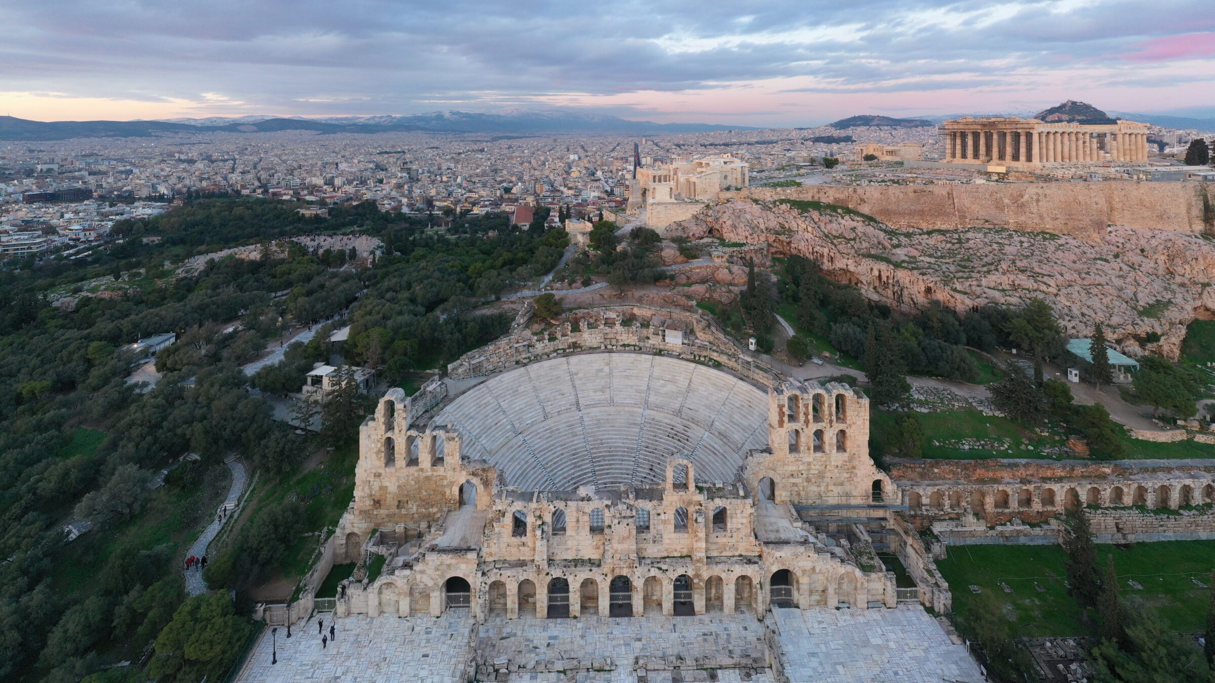 A panoramic view of the Odeon of Herodes Atticus with the Acropolis, Lycabettus Hill, and the modern city of Athens in the background. 