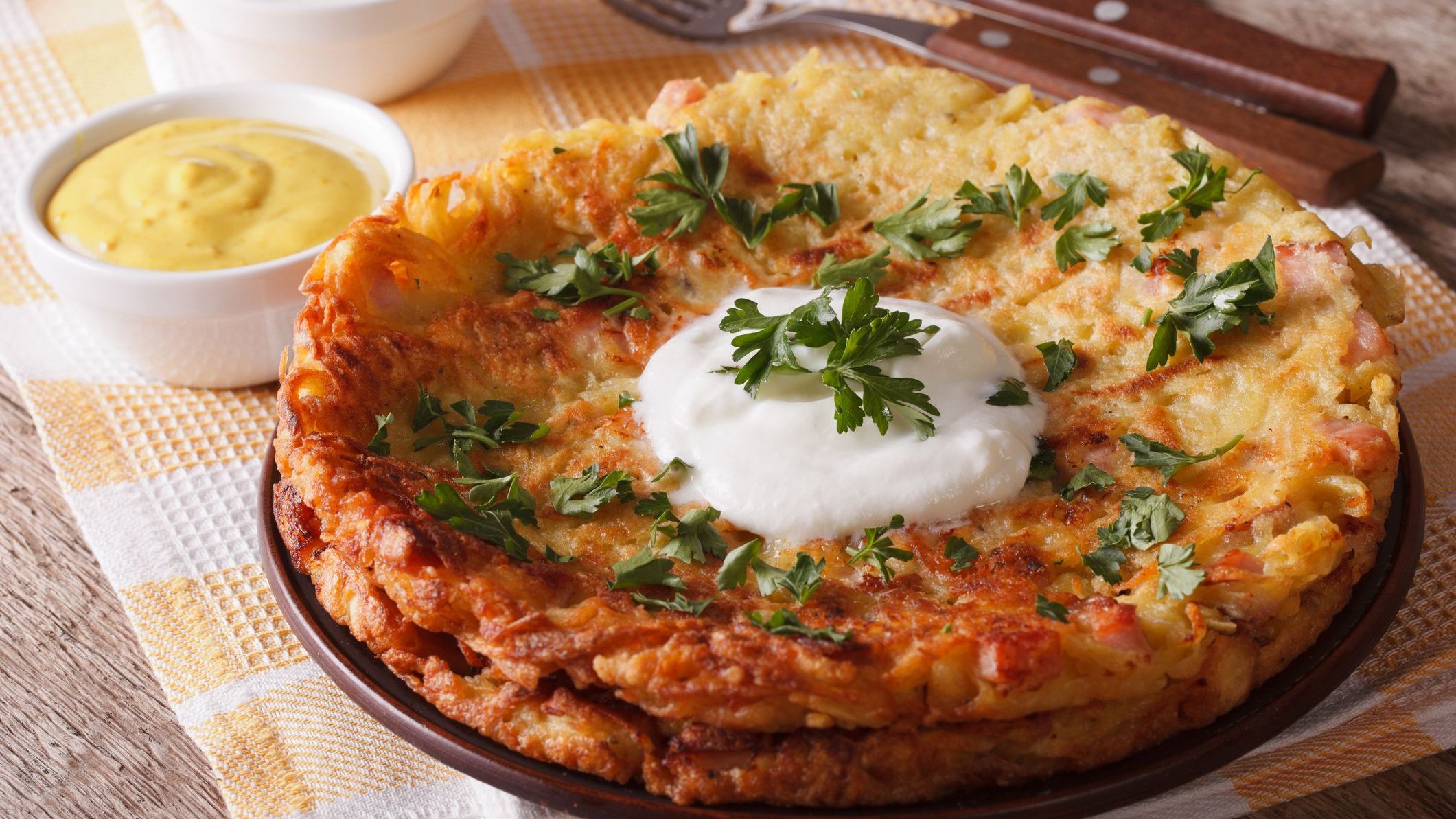 A close-up of Rosti with sauce and parsley on a plate on the table.