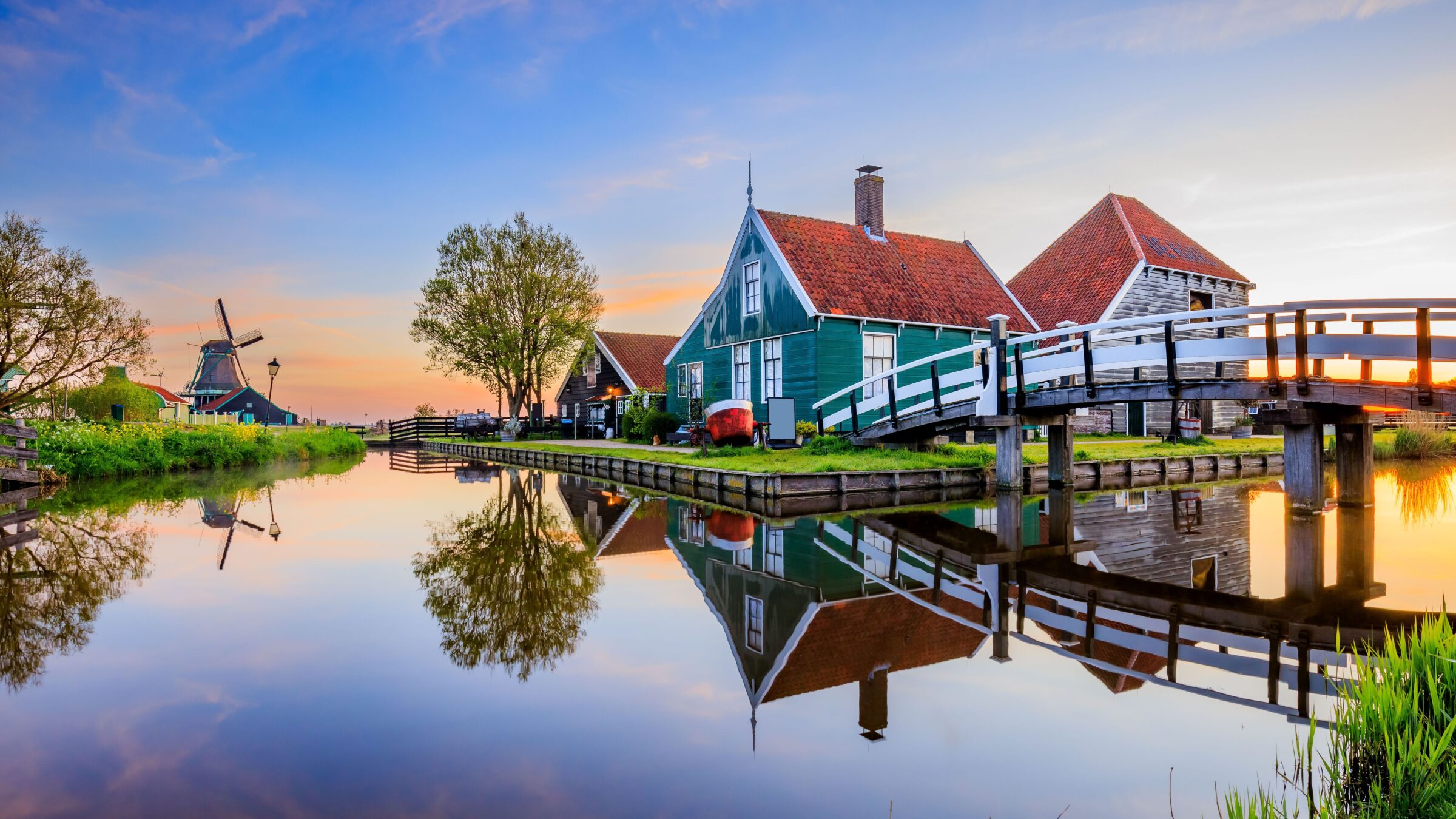 A Dutch windmill and traditional houses at sunrise in Zaanse Schans, one of the best day trips from Amsterdam.