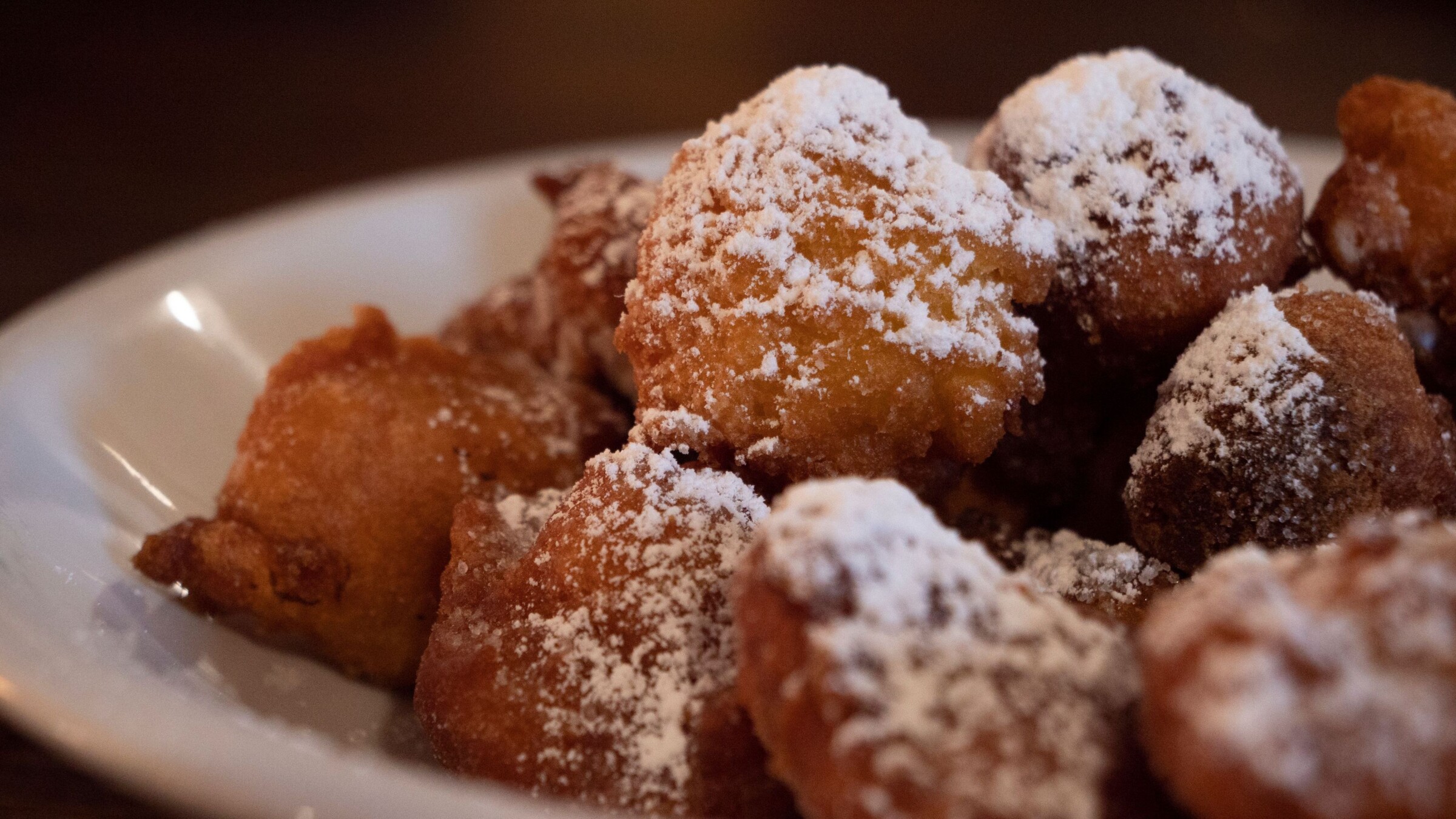 A close-up of fried sweet treats topped with icing sugar. 