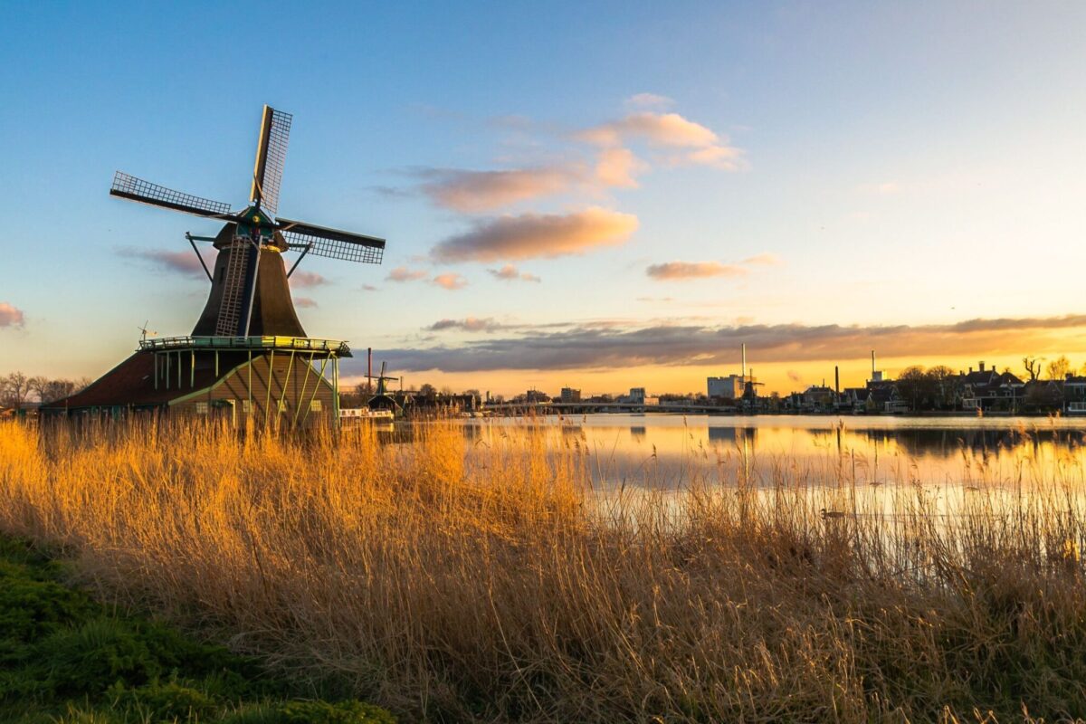 A traditional windmill in the Dutch countryside at sunset.