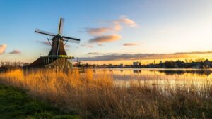 A traditional windmill in the Dutch countryside at sunset.