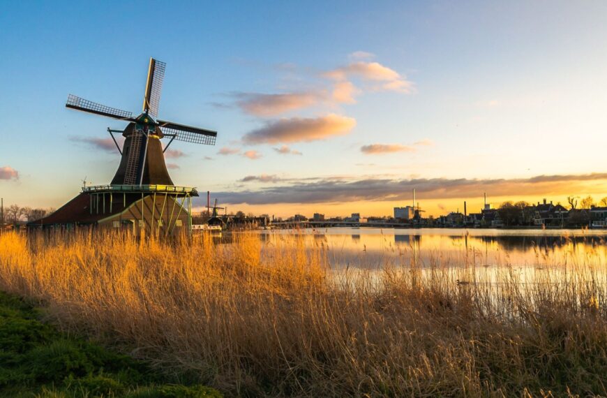 A traditional windmill in the Dutch countryside at sunset.