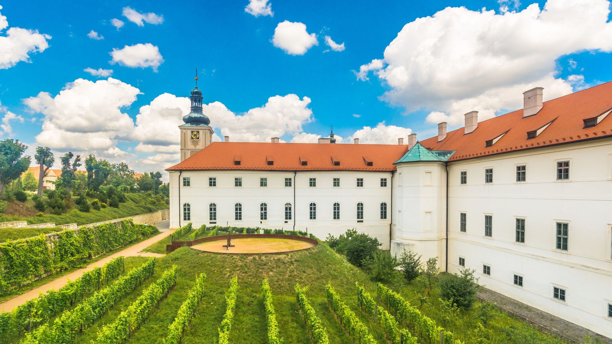 A scenic view of the Gallery of the Central Bohemian Region (GASK) in Kutná Hora, with a lush vineyard in the foreground, highlighting the town’s cultural and historical charm.