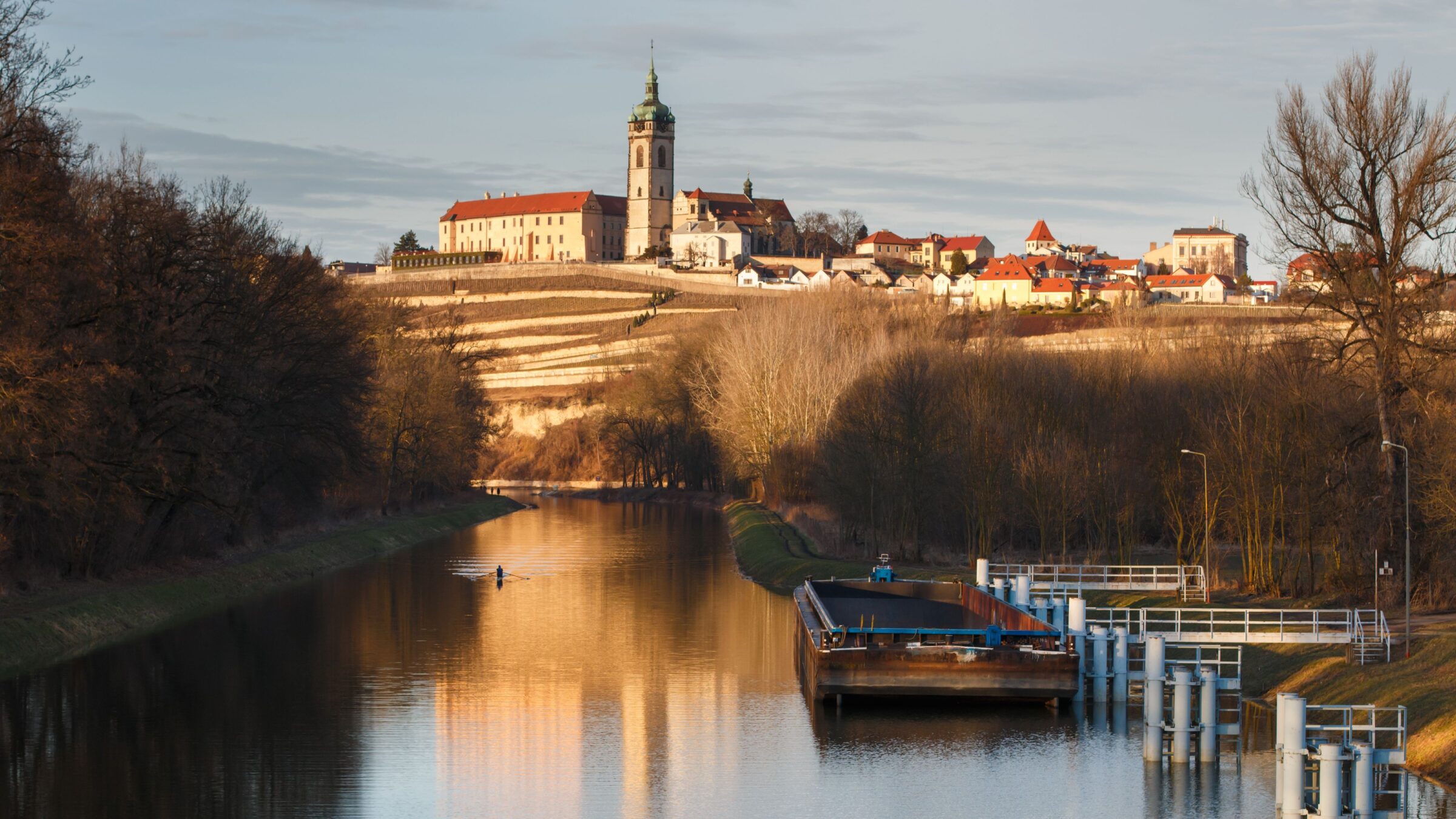 A quaint town on a hill in the background and a river in the foreground.