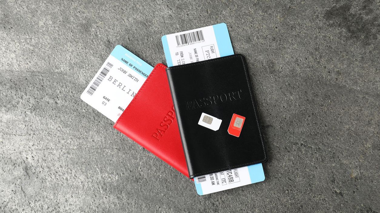 Passports with tickets and SIM cards on a grey surface.