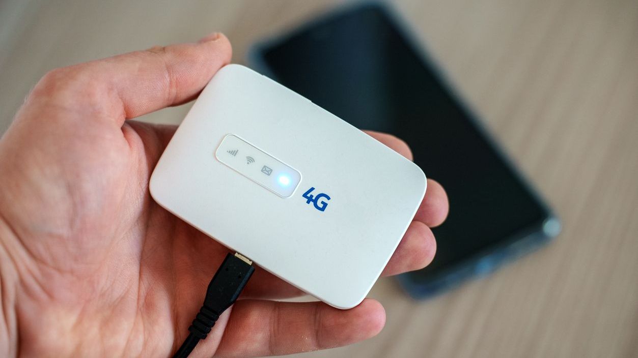 A hand holding a modern wireless pocket 4g wifi modem.