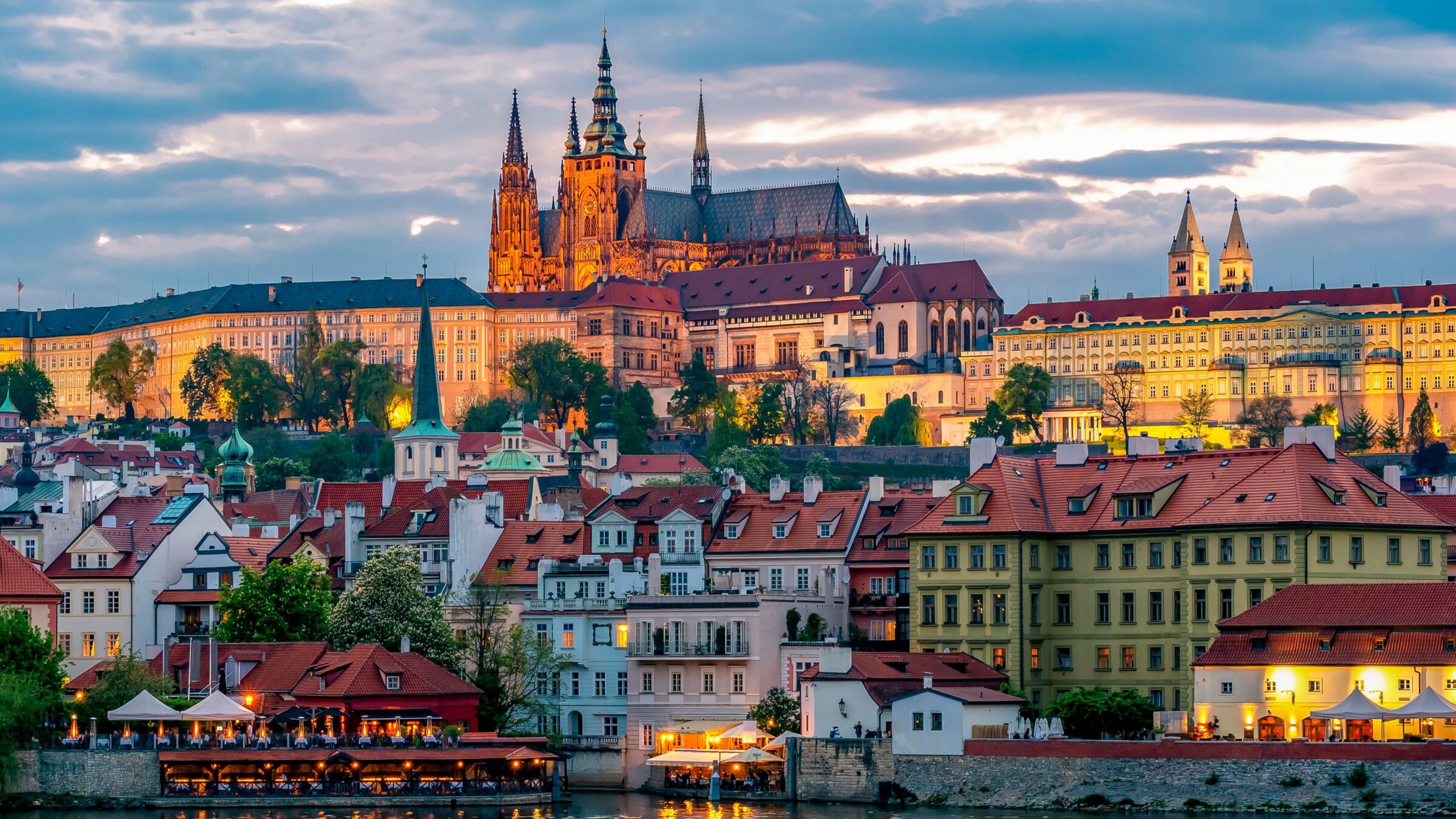 Prague's buildings illuminated in the blue hour with the Castle dominating the skyline.