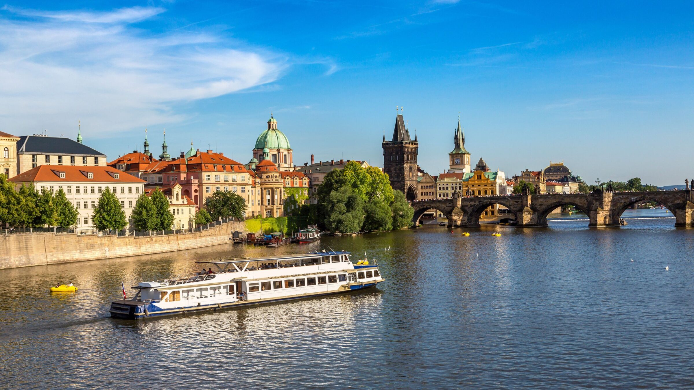A boat on the Vltava River with the Charles Bridge in the background.