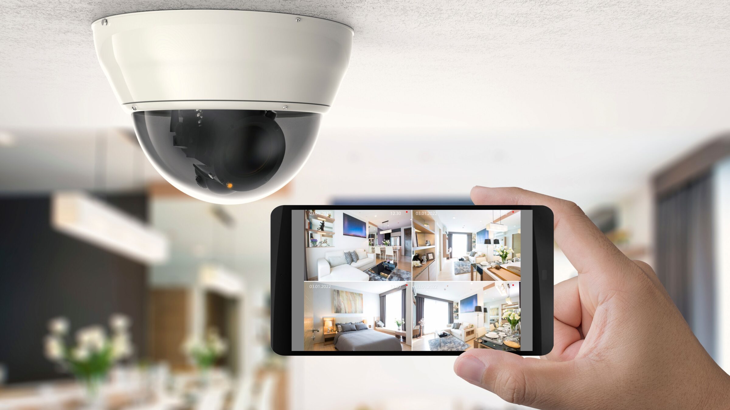 A hand holding a smartphone with security camera snapshots on the screen.