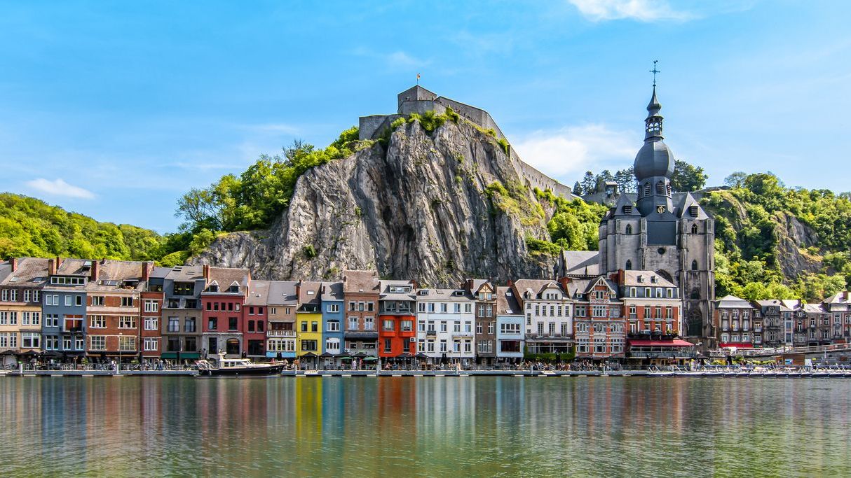 Colorful buildings and a citadel along the Meuse River in Dinant, Wallonia, one of the best places to visit in Belgium.