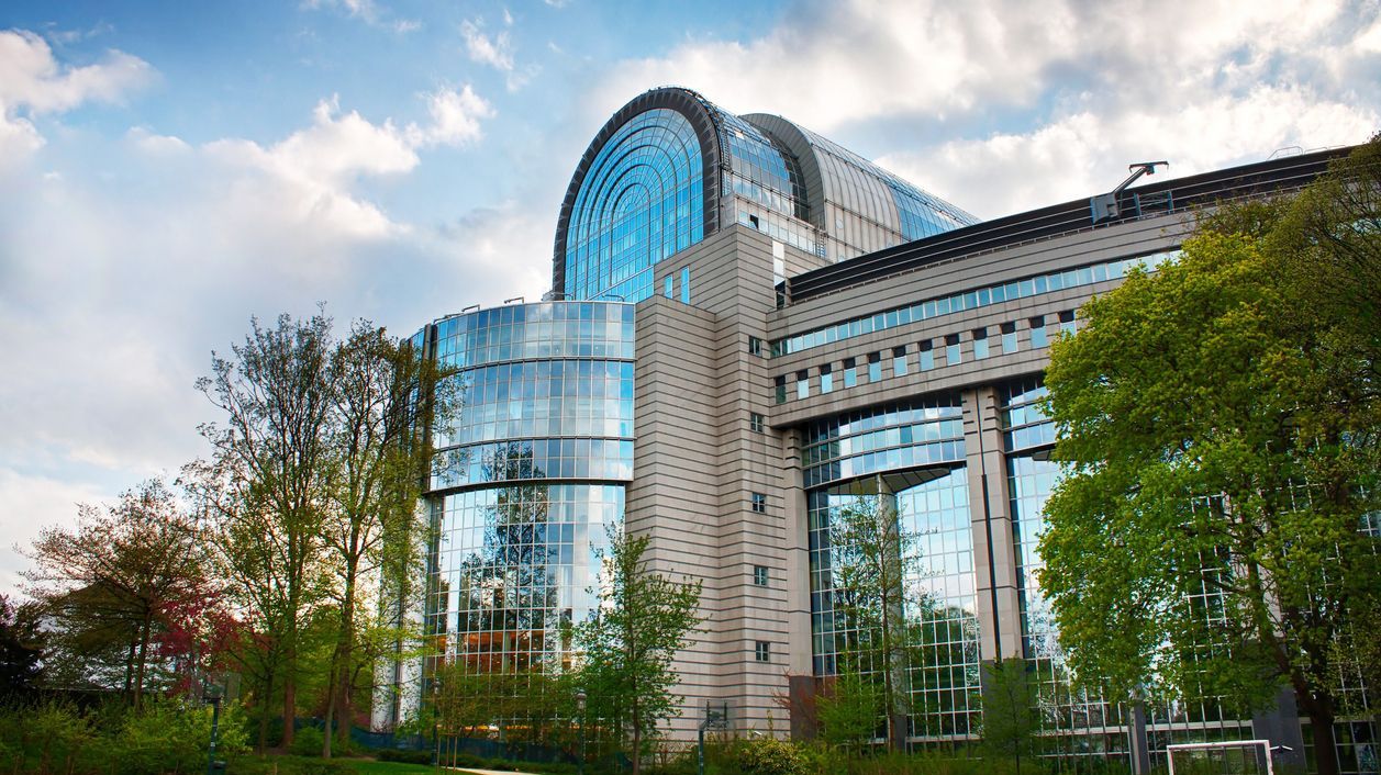 A modern building made of glass and steel, surrounded by trees.