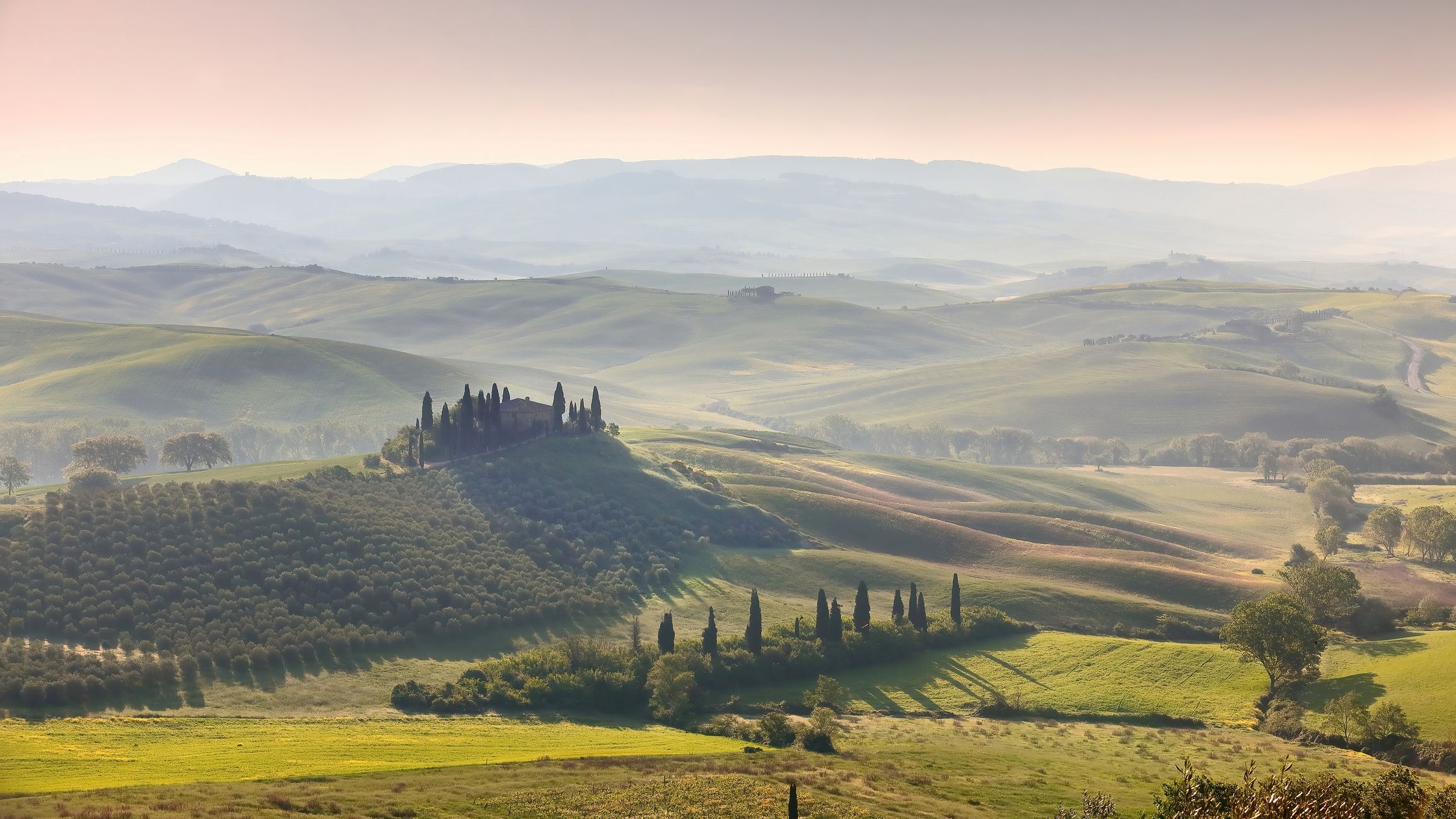 A misty sunrise over Val d'Orcia and its rolling hills.