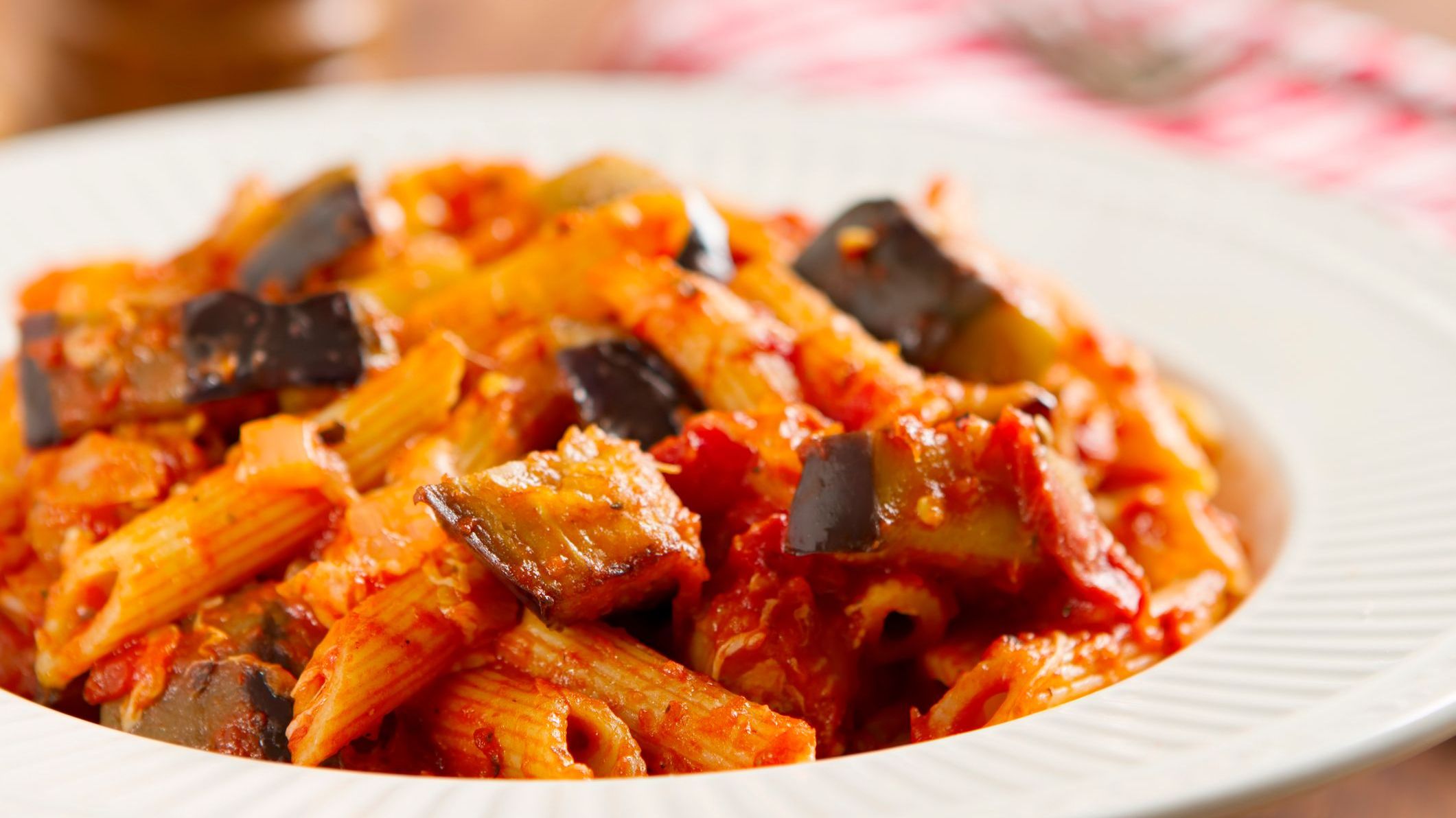 A close-up of the classic Sicilian dish made with rigatoni pasta, fresh eggplant, onion, basil, olive oil, and mozzarella cheese.