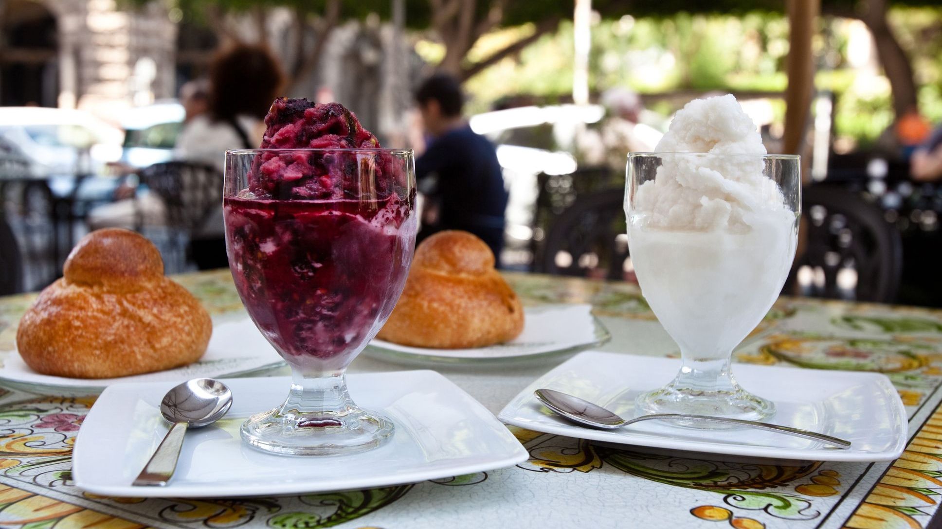 Two glasses filled with Granita - one purple, one white - and two brioche buns. 