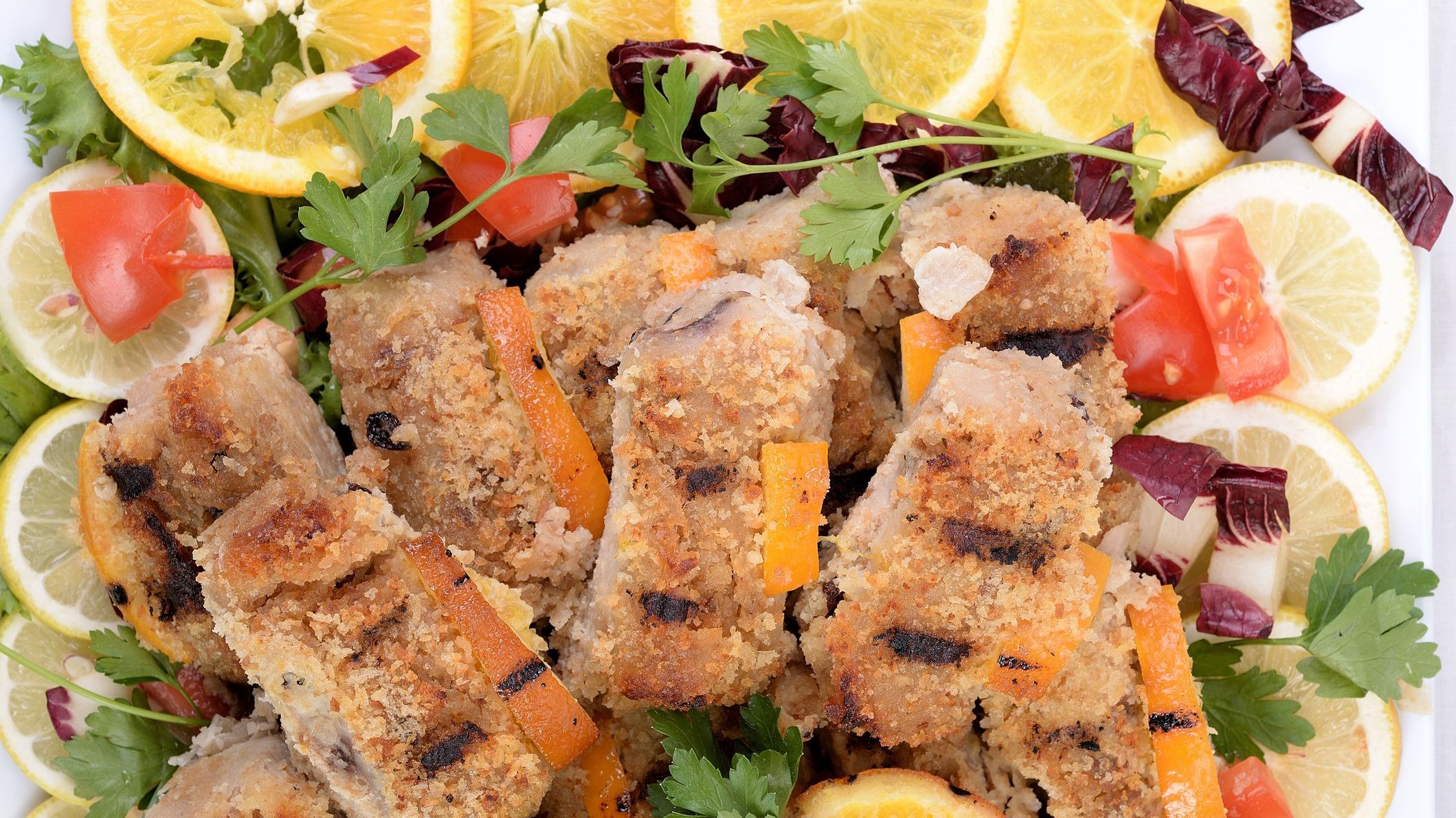 A close-up of swordfish rolls with lemon slices on the sides. 