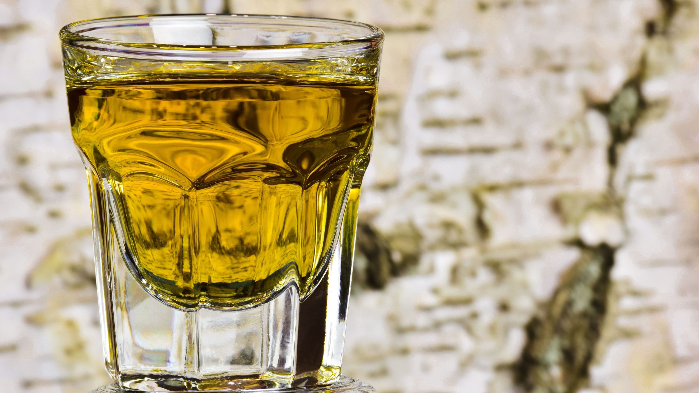 A close-up of a glass with a golden-hued drink. 