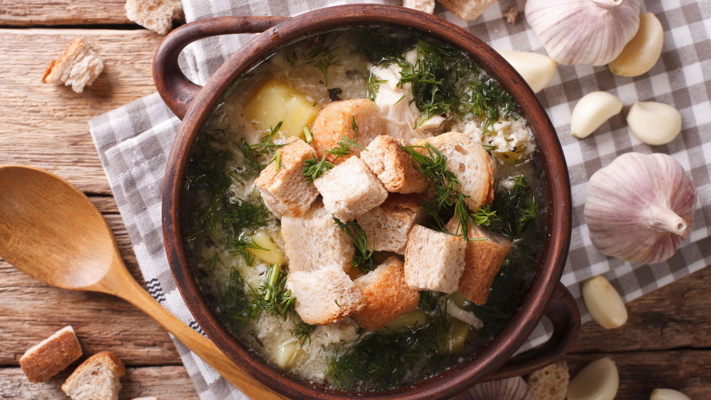 A clay bowl of soup topped with croutons. 