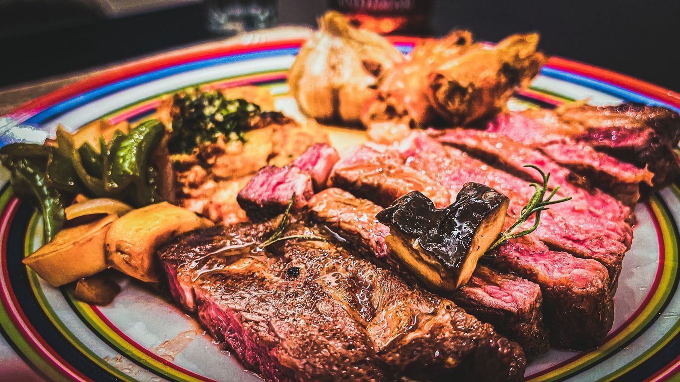 A close-up shot of a Bistecca alla Fiorentina in a colorful plate on a table.