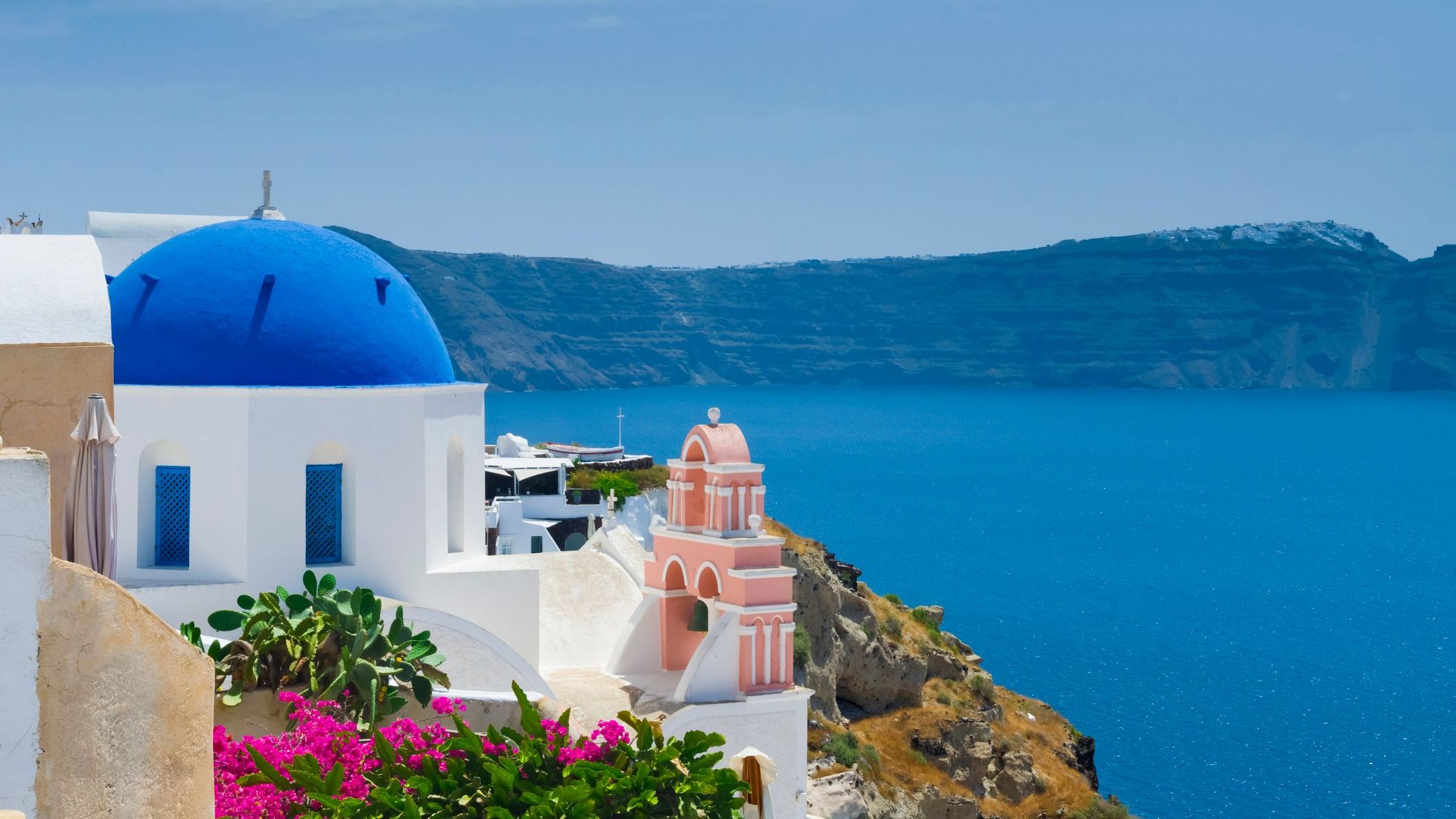 Santorini's iconic blue-domed church with the caldera in the background. 