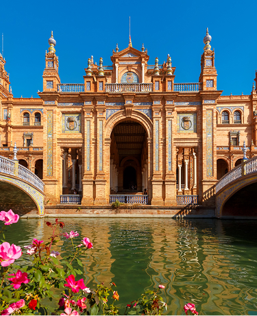Spain Square or Plaza de Espana in Seville in the sunny summer day, Andalusia, Spain. Flower beds, bridges and channel in the foreground