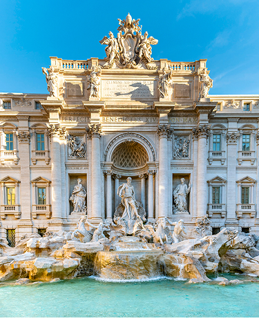The Trevi Fountain (Fontana di Trevi) in Rome, Italy, featuring the grand Baroque façade of Palazzo Poli with intricate marble sculptures, including Oceanus standing in a shell-shaped chariot pulled by sea horses, as turquoise water cascades into the large basin crowded with visitors tossing coins.
