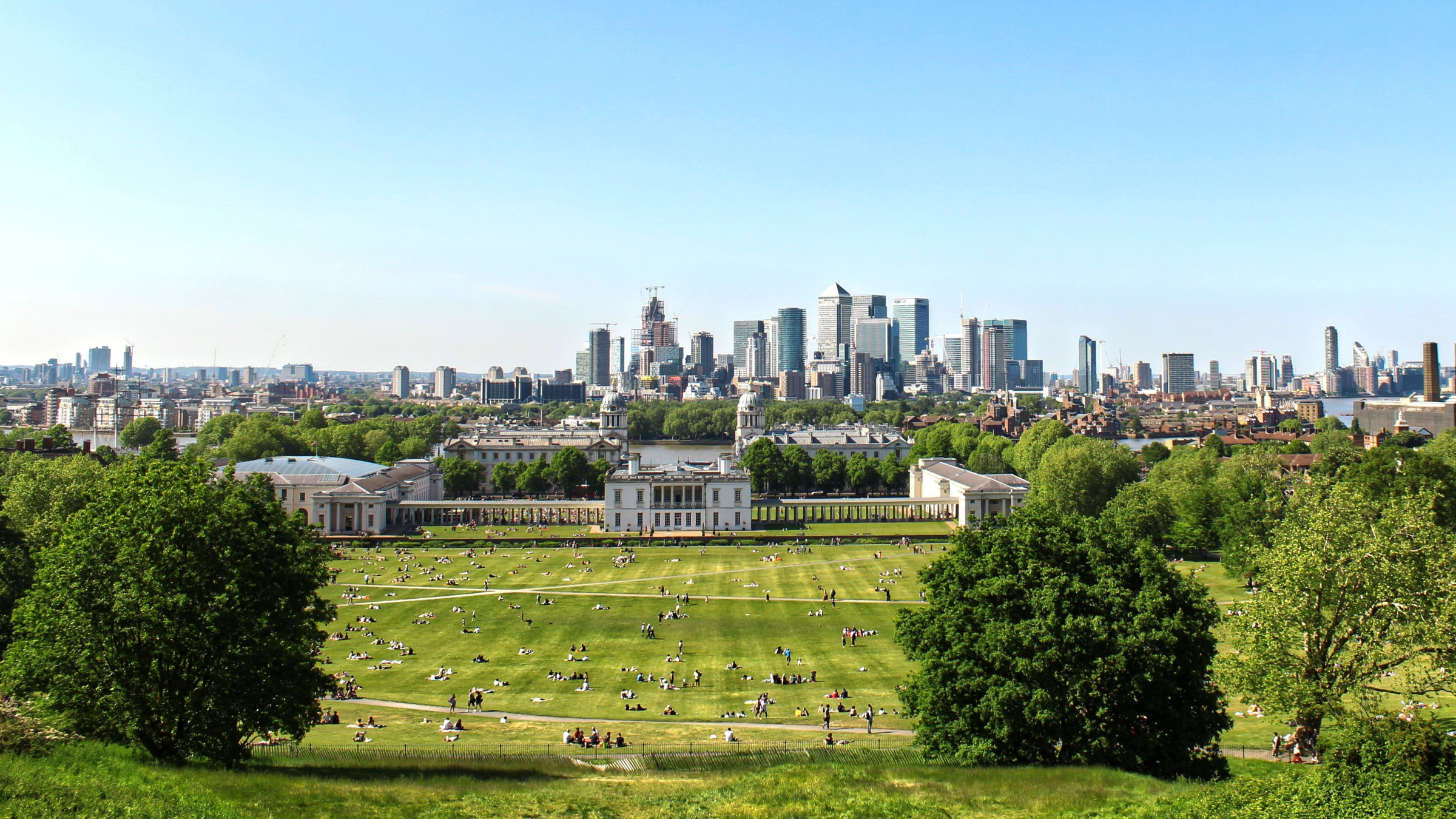 A panoramic view of Greenwich Park with London's skyline in the background.