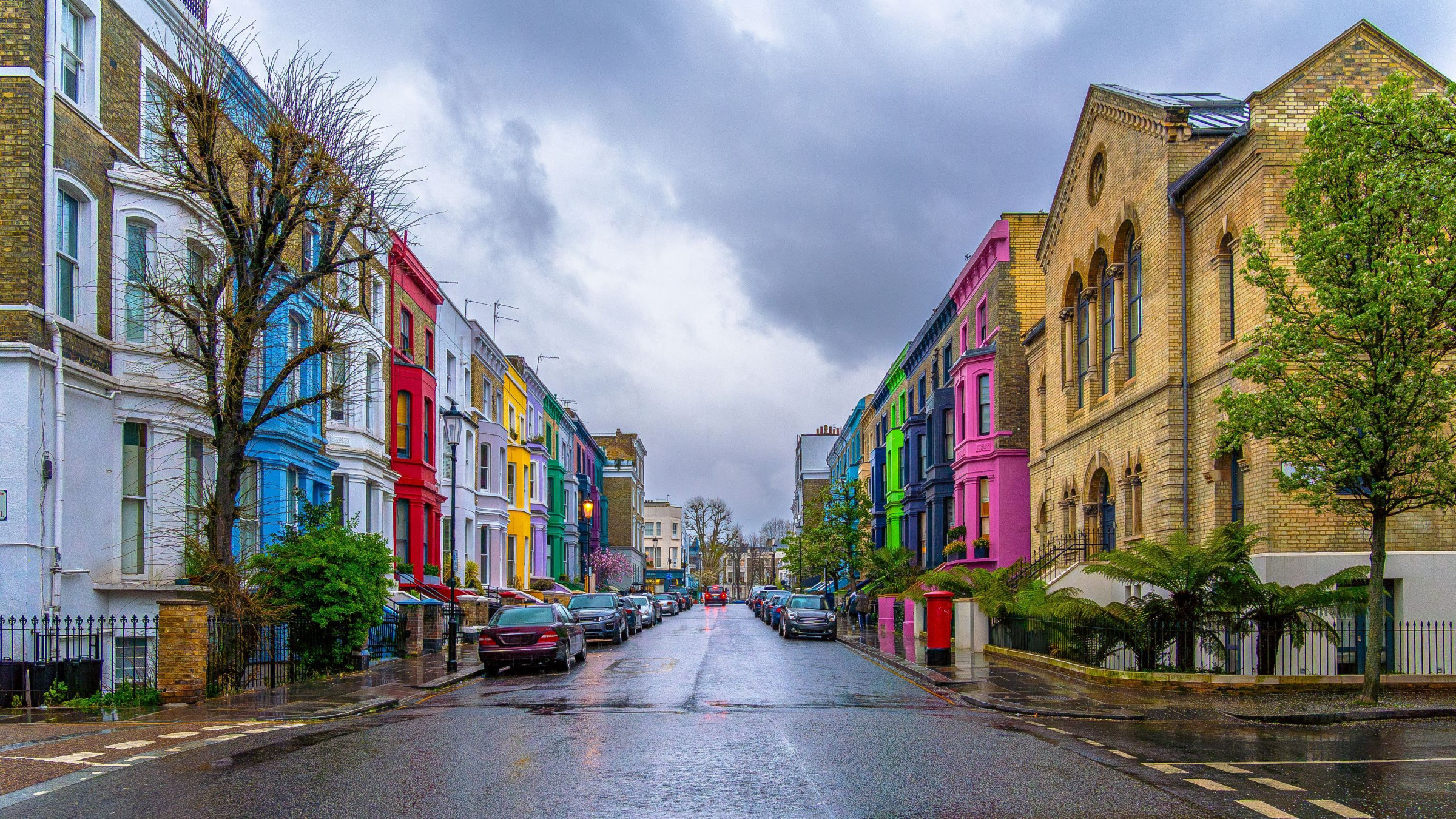 A street lined with colorful buildings on both sides, under a cloudy and rainy sky.