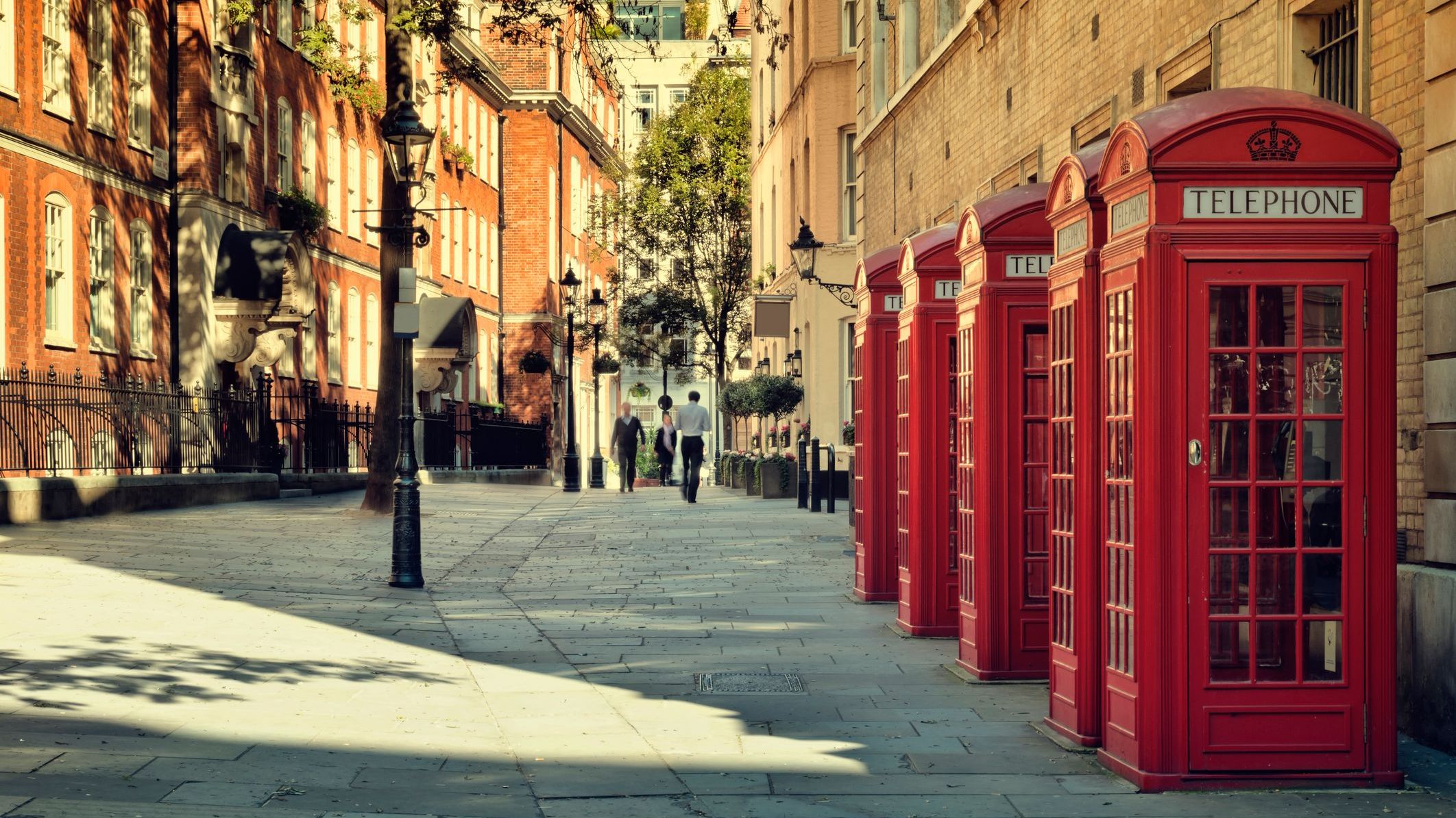 A street with three iconic red phone booths near Covent Garden, London.