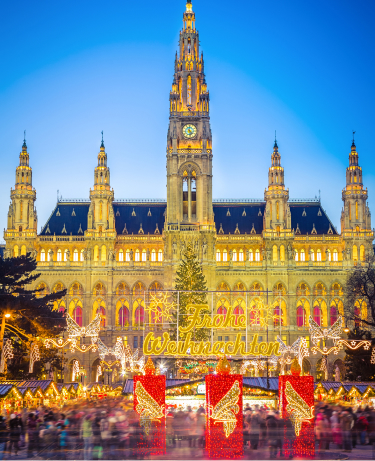 Festive European Christmas market with illuminated wooden stalls, holiday decorations, and crowds browsing seasonal gifts at night.