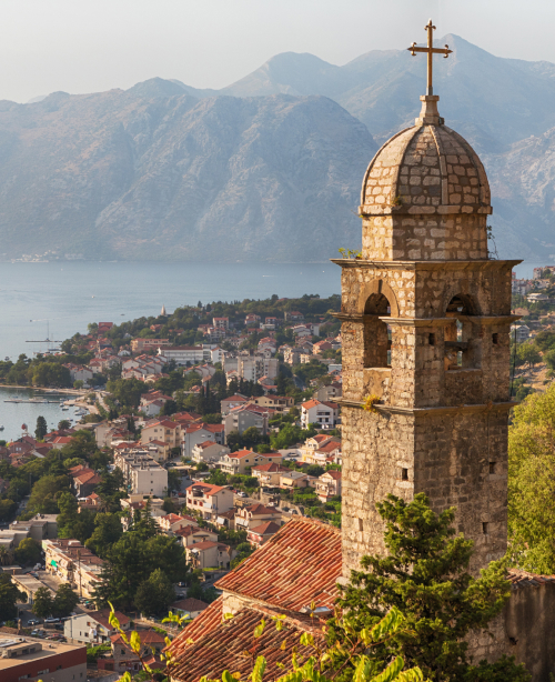 Historic old town of Kotor nestled between mountains and the Adriatic Sea, with stone buildings and fortified walls.