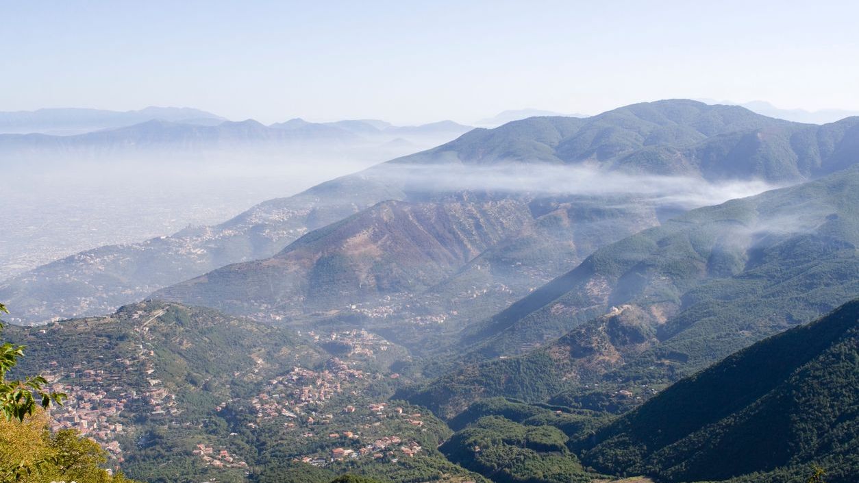 A panoramic view of a green mountain dotted with small villages.