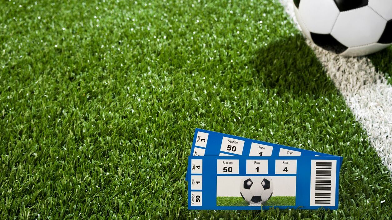 A pair of Tickets sitting in front of a Soccer Ball on Midfield line.