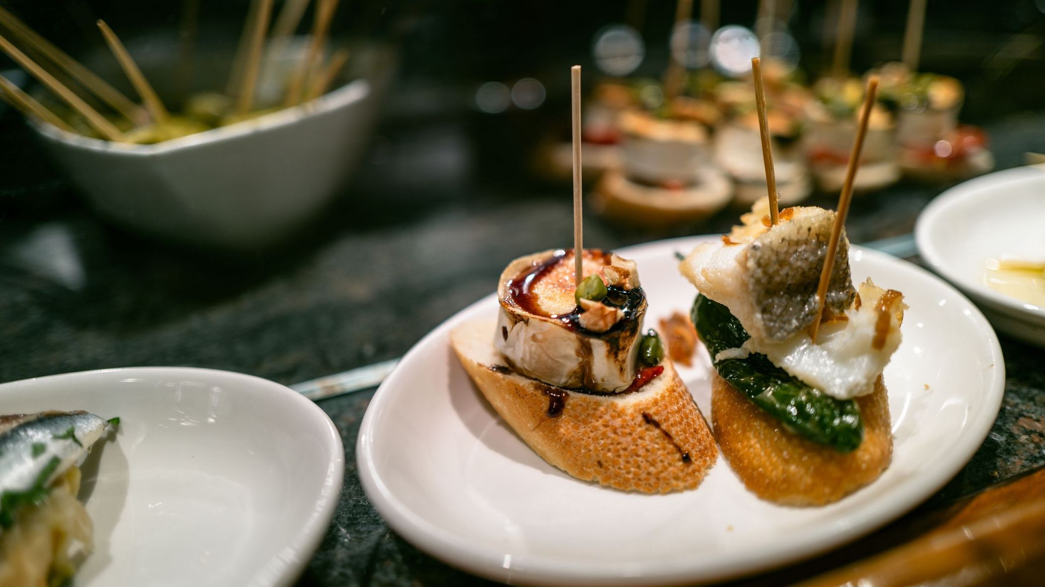 Two pintxos in a white plate. 