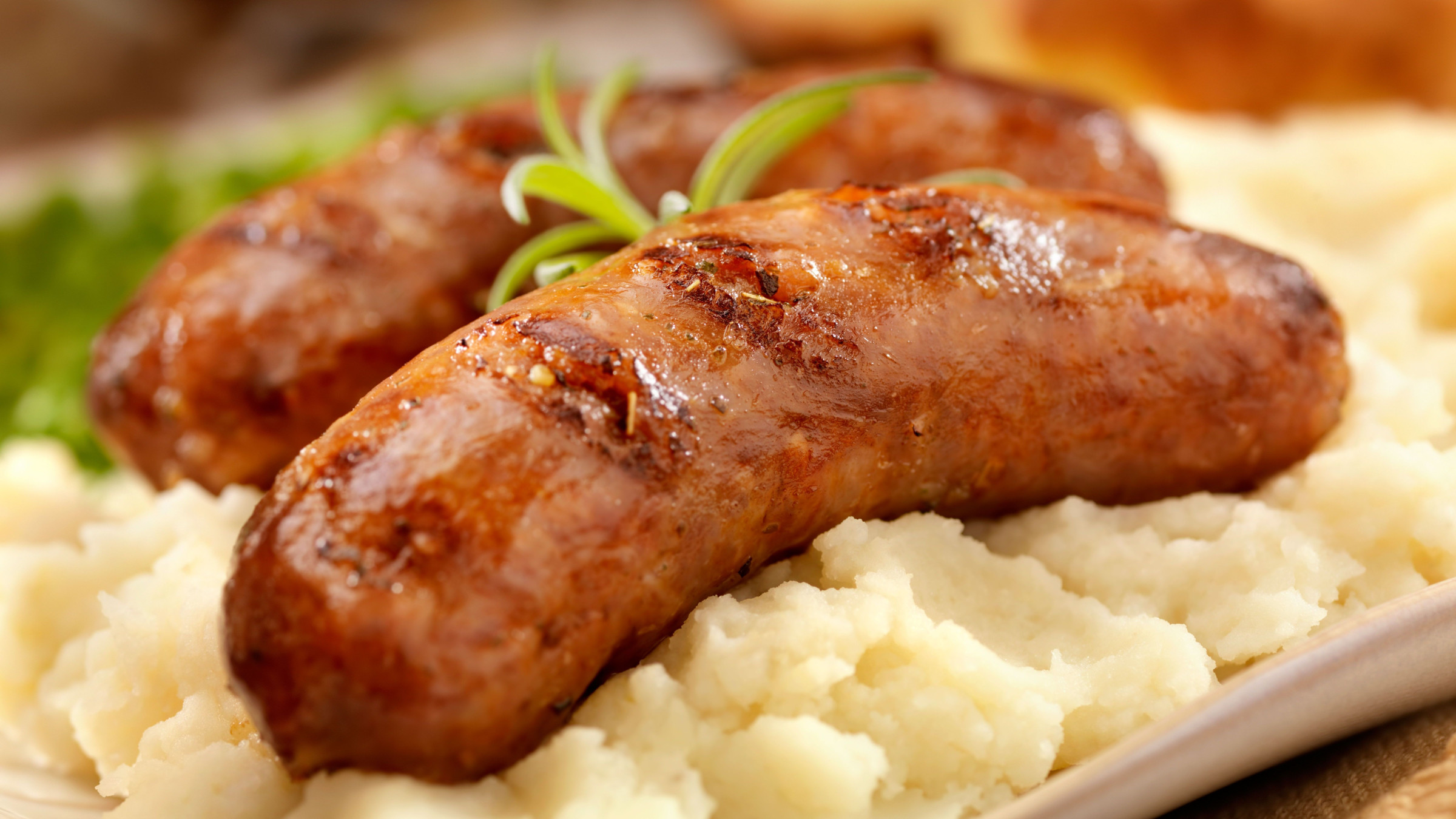 A close-up of mashed potatoes with two sausages on top, one of the best British dishes if you're wondering what to eat in the UK.
