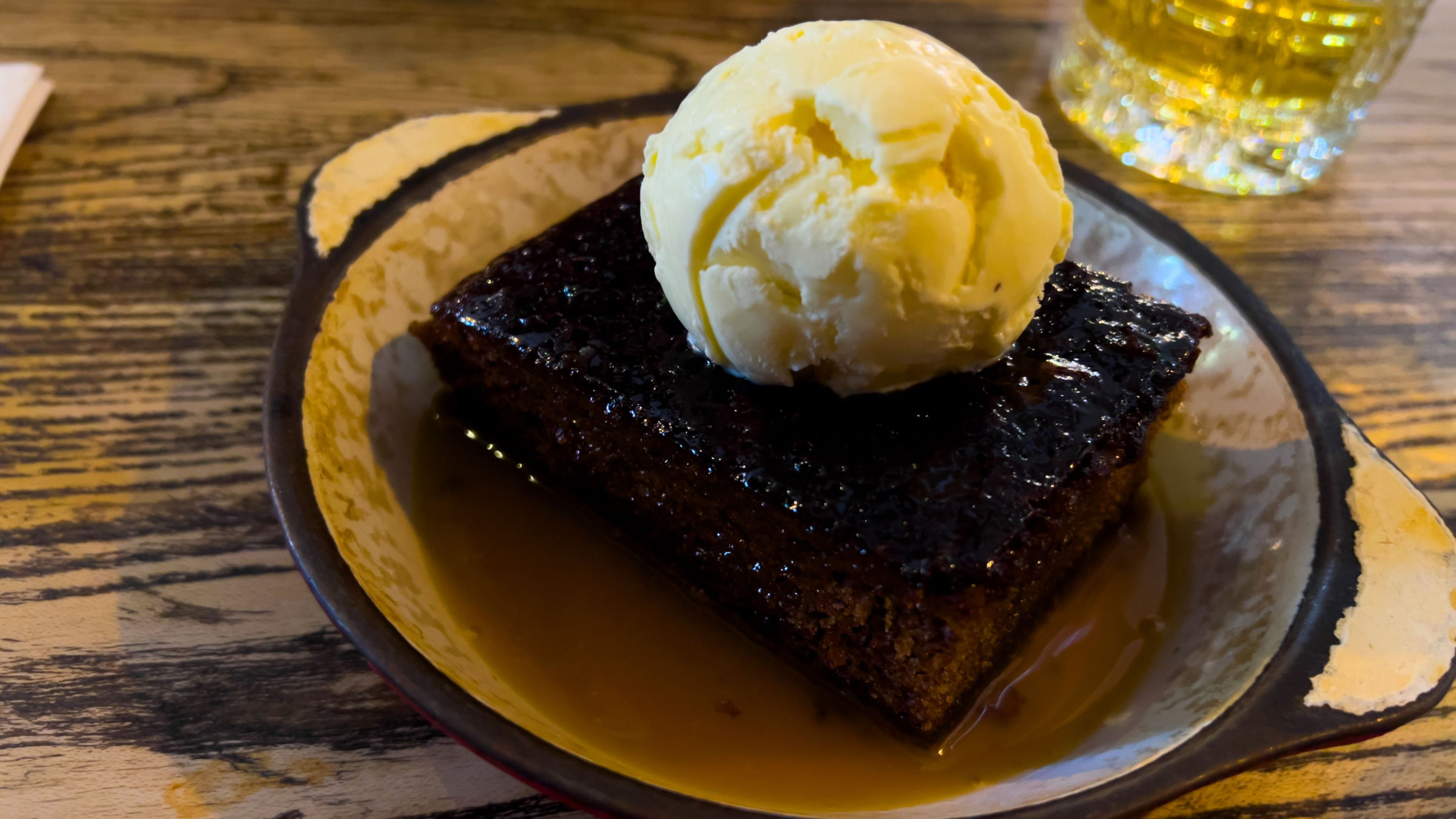 A large piece of cake with a scoop of vanilla ice-cream on top. 