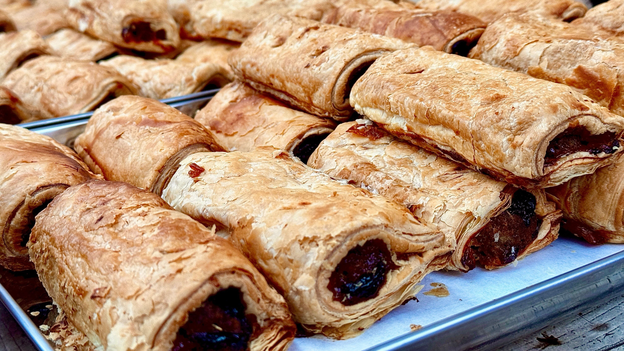 A close-up of many sausage rolls on a tray. 